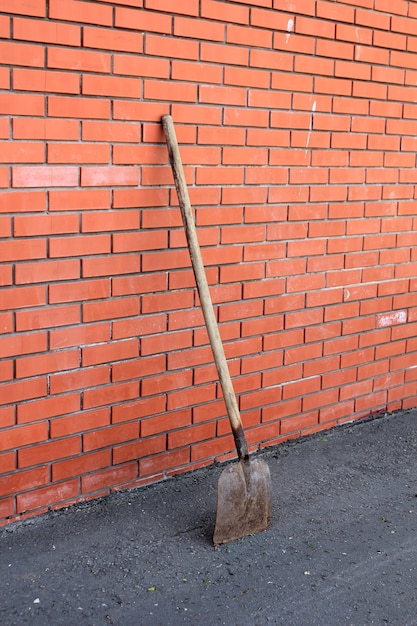 La pala está cerca de la pared de ladrillo rojo.