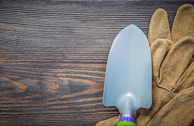 Pala de mano par de guantes de seguridad en la vista superior de la tabla de madera concepto de jardinería.