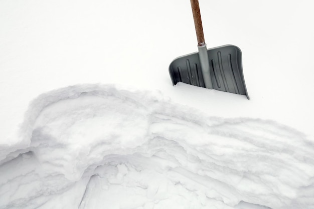 La pala de nieve está atascada en el invierno cubierto de nieve ventisquero