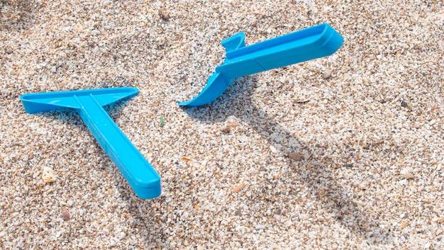 Foto pala de plástico de juguete azul y rastrillo en la arena blanca de la playa