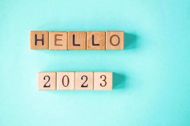 La palabra 2023 está hecha de bloques de madera en el fondo turquesa Feliz Año Nuevo