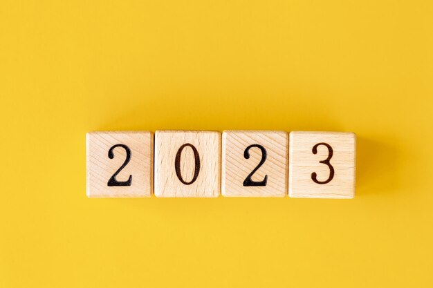 La palabra 2023 está hecha de bloques de madera sobre el fondo amarillo Feliz Año Nuevo