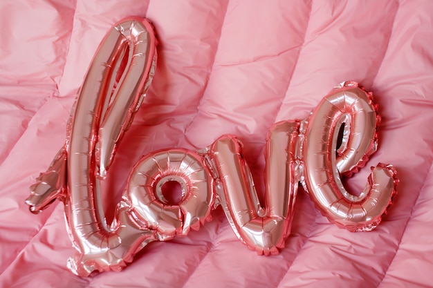 Palabra de amor de globo inflable rosa sobre fondo rosa. El concepto de romance, el día de San Valentín. Globo de papel de oro rosa amor