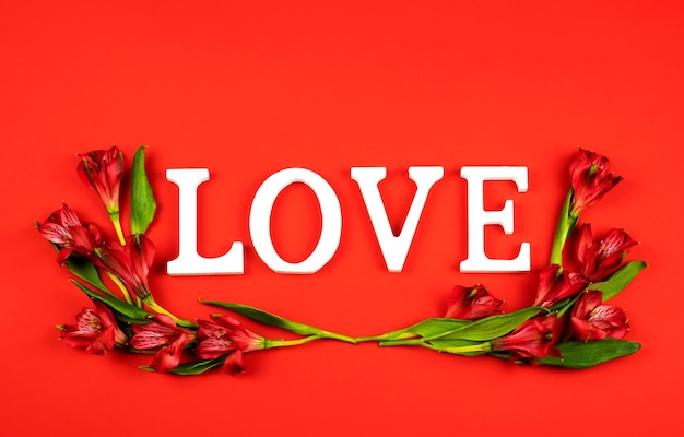 La palabra amor en rojo con flores de alstroemeria.