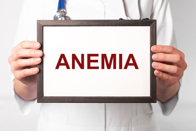 Palabra de anemia en el marco de papel en la mano del médico