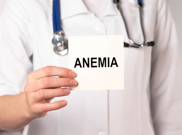 Palabra de anemia en papel en la mano del médico