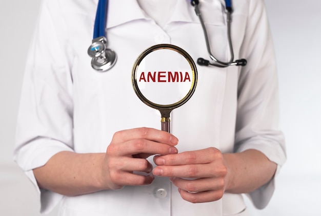 Palabra de anemia a través de la lupa en la mano del médico