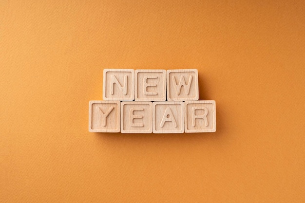 La palabra Año Nuevo está llena de cubos de madera con letras sobre un fondo naranja Tarjeta de felicitación de Año Nuevo