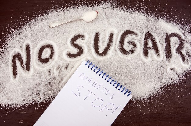 Foto la palabra sin azúcar está escrita en azúcar granulada blanca. concepto de daño por azúcar.
