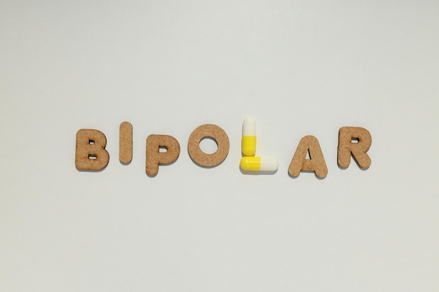 La palabra bipolar con pastillas amarillas sobre un fondo claro