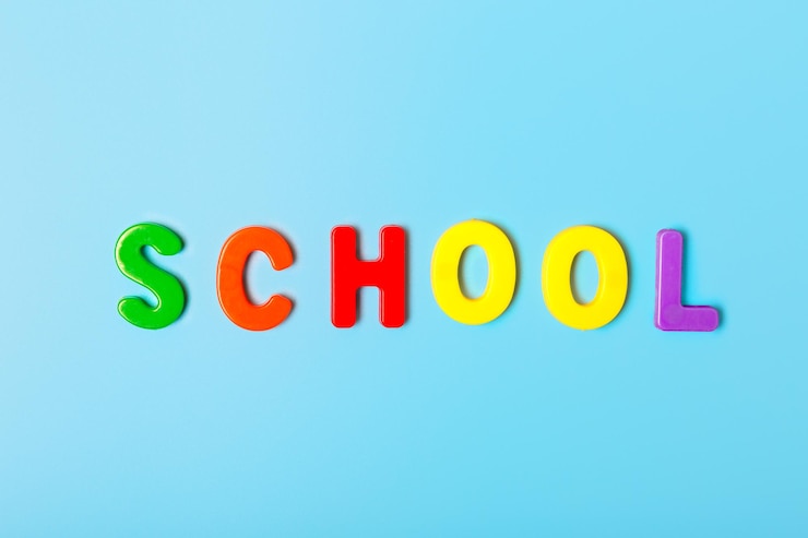 Foto la palabra escuela de letras multicolores sobre un fondo azul concepto de regreso a la escuela concepto de estudio concepto de tienda de papelería copiar espacio plano vista superior minimalismo