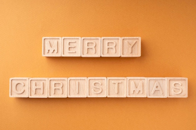 La palabra Feliz Navidad está escrita en cubos de madera Cubos de madera con letras sobre un fondo naranja Tarjeta de Año Nuevo