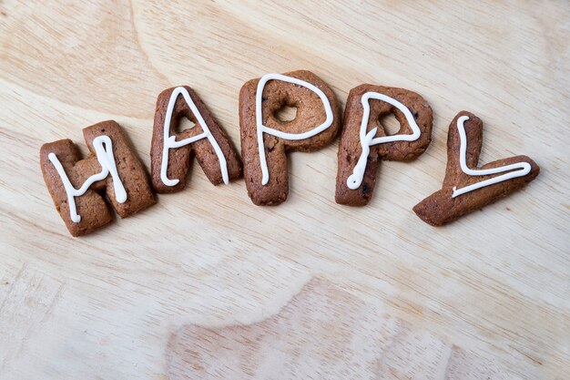 La palabra feliz sobre un fondo de madera Galletas de jengibre con glaseado Tartas caseras