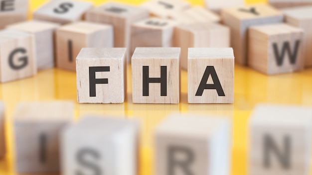 La palabra FHA está escrita en una estructura de cubos de madera. bloques sobre un fondo brillante. concepto financiero. enfoque selectivo. FHA - abreviatura de Finance Houses Association