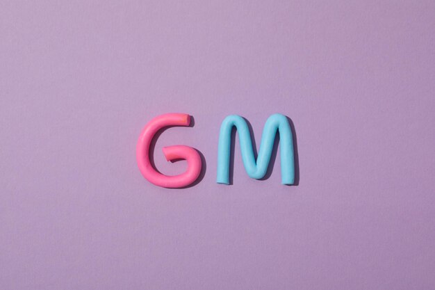 La palabra GM colocada en plasticina de color sobre un fondo púrpura