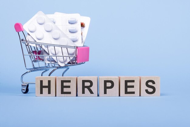 La palabra HERPES en cubos de madera sobre un fondo azul con pastillas en un carrito de compras