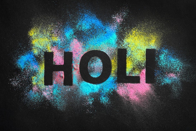 Palabra HOLI escrita en polvos de colores sobre fondo oscuro