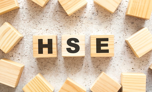 La palabra HSE consta de cubos de madera con letras, vista superior sobre un fondo claro. Espacio de trabajo.