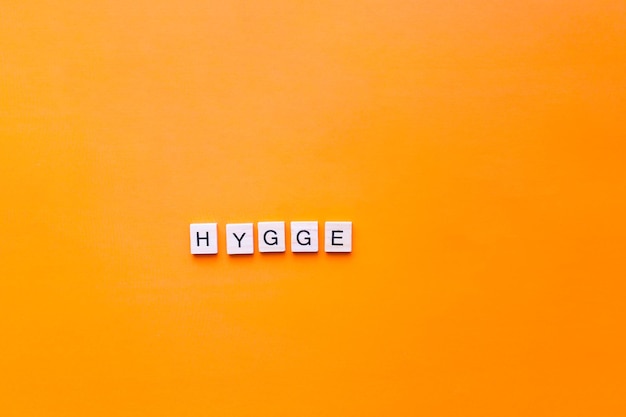 La palabra hygge hecha de letras de madera sobre un fondo naranja