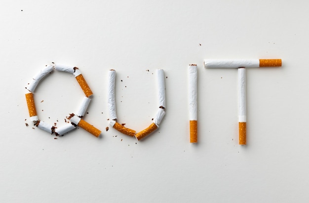 Palabra de inscripción QUIT hecha de vista superior de cigarrillos endecha plana