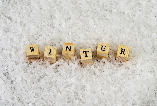 Foto la palabra invierno hecha de letras en cubos de madera sobre una nieve