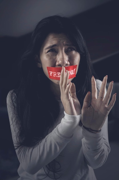 Foto palabra de libertad cubriendo la boca de una mujer maltratada