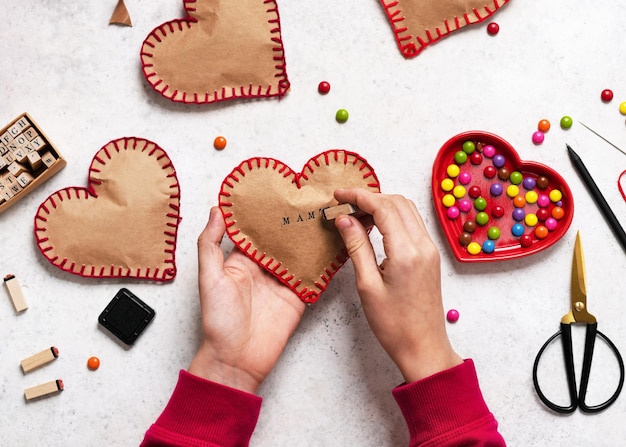 Palabra MAMA estampada por los niños a mano en el corazón de papel con tinta negra