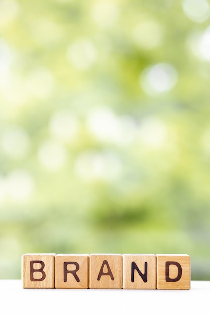 La palabra de marca está escrita en cubos de madera sobre un fondo verde de verano Primer plano de elementos de madera