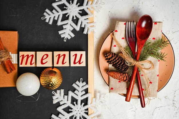 Foto la palabra menú sobre un fondo de navidad un plato con cubiertos y adornos navideños copos de nieve un ...