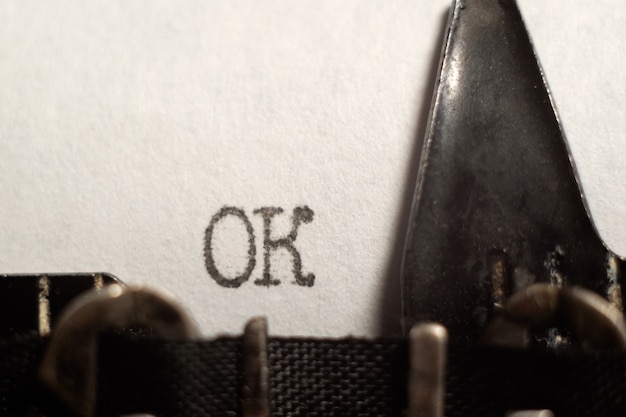 La palabra "ok" escrita en una hoja de papel blanco, usando una máquina de escribir retro