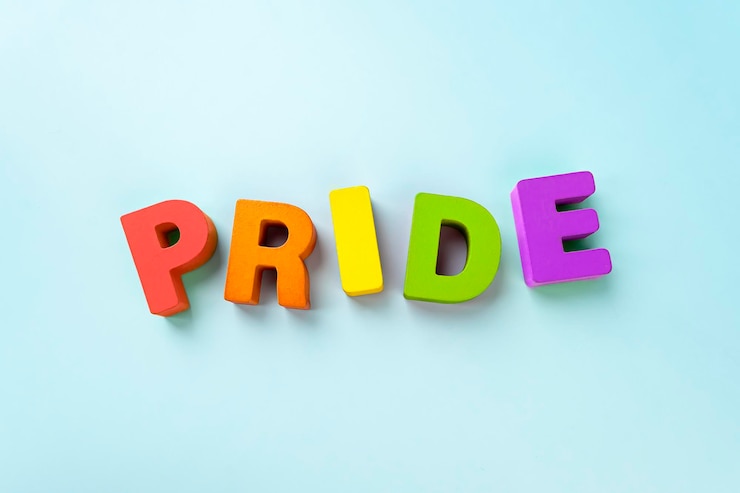 Foto palabra orgullo en letras sueltas sobre un fondo azul.