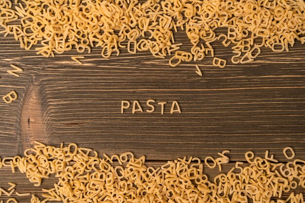 La palabra "pasta" se presenta a partir de pasta pequeña sobre un fondo de madera