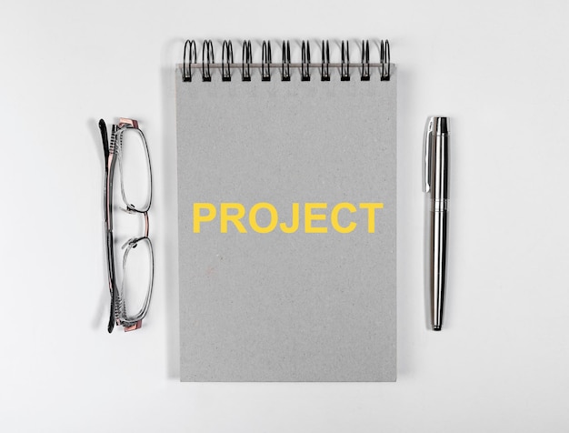 Palabra de proyecto en bolígrafo y gafas de bloc de notas de negocios