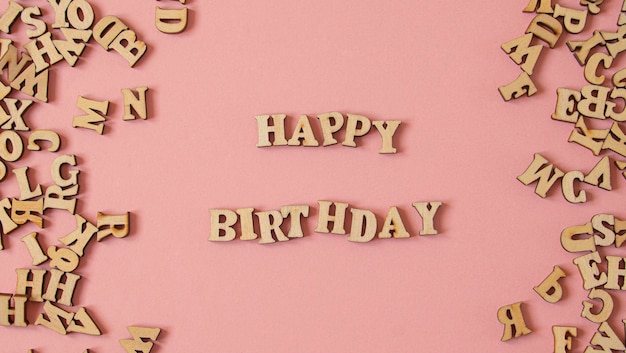 Palabra quotFeliz cumpleañosquot escrito en inglés con letras de madera sobre un fondo rosa