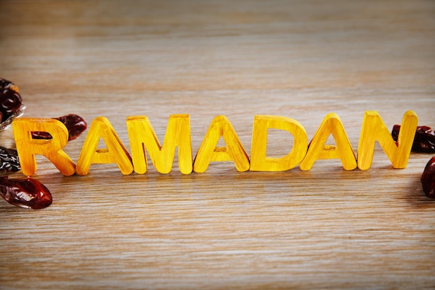 Palabra de ramadán con letras de madera y dátiles secos en la mesa
