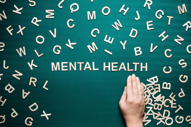 Palabra de salud mental de letras de madera Texto de salud mental sobre fondo verde con muchas otras letras