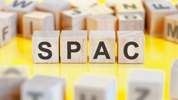 La palabra spac está escrita en una estructura de cubos de madera. bloques sobre un fondo brillante. concepto financiero. enfoque selectivo. spac - abreviatura de empresa de adquisición de fines especiales