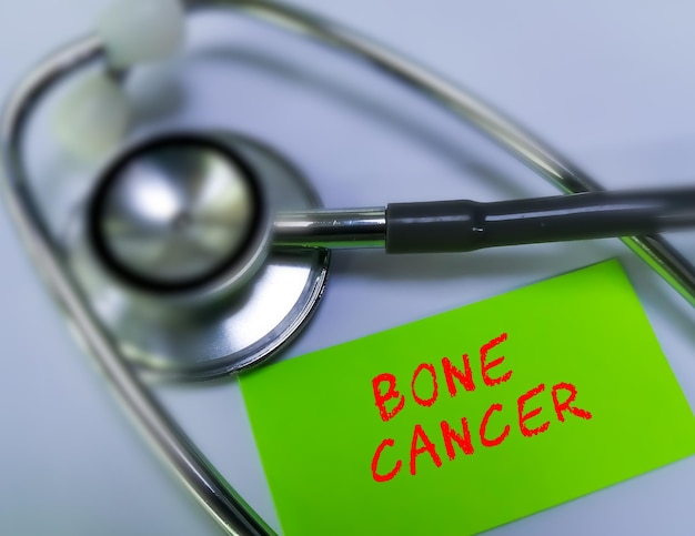 Palabra de término médico de cáncer de hueso en tarjeta verde sobre fondo blanco con estetoscopio. concepto médico.