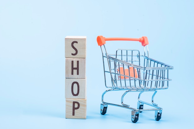 Palabra de tienda de bloque de cubo de madera con mini carrito de compras en azul