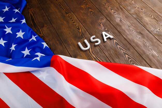 Foto la palabra usa se colocó con letras de metal plateado en la superficie de una tabla de madera con una bandera arrugada de los estados unidos de américa