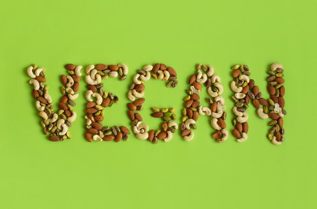 Palabra vegana hecha de nueces sobre un fondo verde