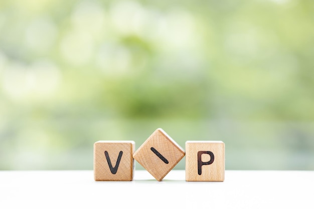 La palabra VIP está escrita en cubos de madera sobre un fondo verde de verano Primer plano de elementos de madera