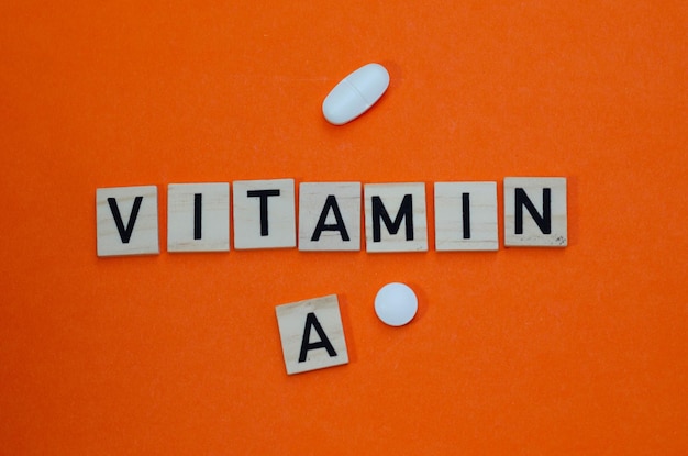 Palabra vitamina c en letras de madera sobre fondo naranja. Concepto de prevención contra resfriados y antio
