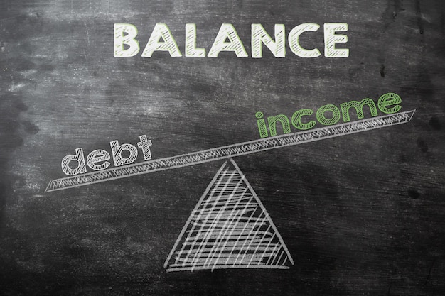 Palabras deuda e ingresos en balanzas en pizarra