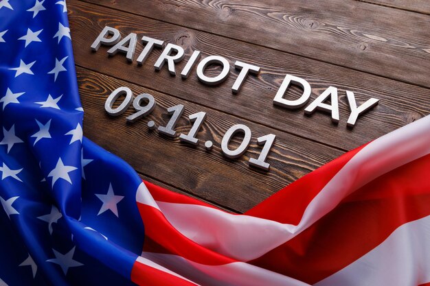 Las palabras día del patriota colocadas con letras de metal plateado en la superficie de una tabla de madera con una bandera de estados unidos arrugada