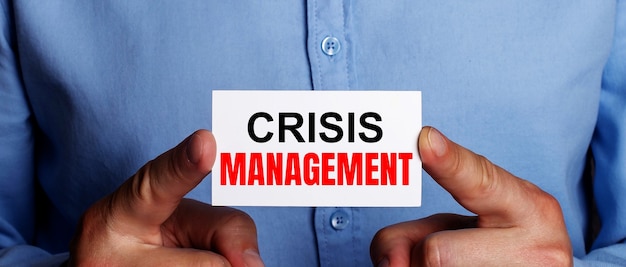 Foto las palabras gestión de crisis están escritas en una tarjeta de presentación blanca en manos de un hombre