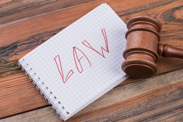Palabras de leyes de primer plano escritas en el bloc de notas en espiral y martillo