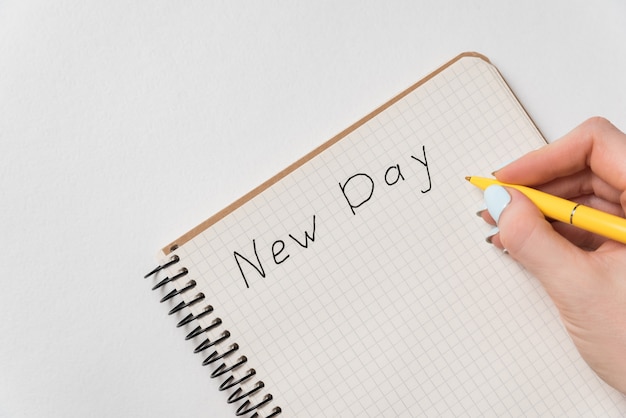 Palabras nuevo día en el cuaderno. Mujer mano escribiendo en el cuaderno. Escrito. Fondo blanco