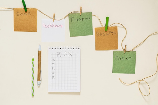 Palabras objetivo, problemas, tareas, finanzas, resultados, plan en pegatinas de papel con pinzas para la ropa en una cuerda y un cuaderno