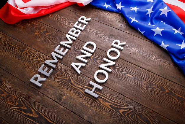 Las palabras recuerdan y honran colocadas con letras de metal plateado sobre fondo de madera con la bandera de EE.UU. en el lado derecho